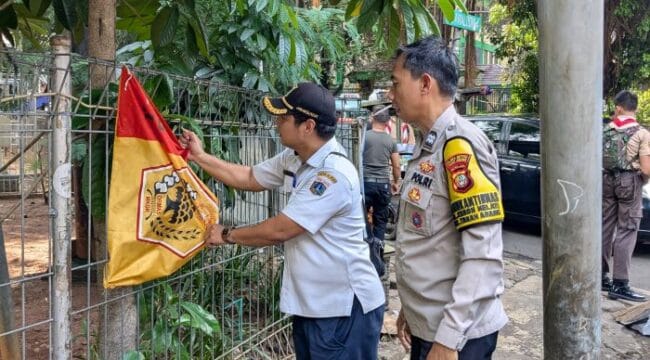 salah seorang petugas gabungan saat menertibkan salah satu bendera ormas .(Foto : Humnas Polres Jakpus)