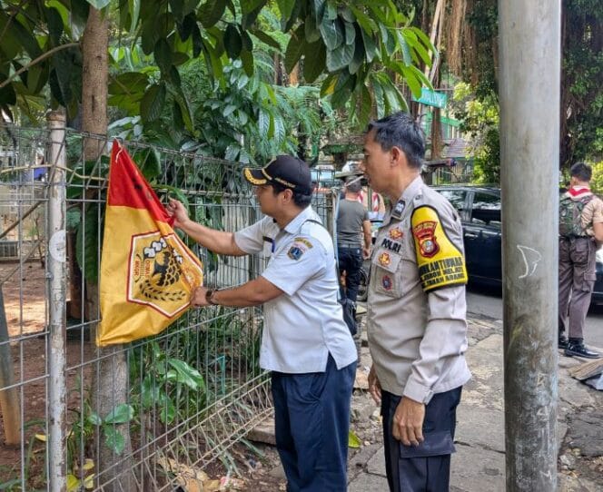
					salah seorang petugas gabungan saat menertibkan salah satu bendera ormas .(Foto : Humnas Polres Jakpus)