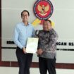 Ketua Sidang Komisi KPPU Budi Joyo Santoso daat menyerahkan dokumen penetapan Program Kepatuhan Persaingan Usaha Kepada Presiden Direktur PT PLI Wen Krisnadi (Foto : Sirhan)