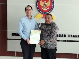 Ketua Sidang Komisi KPPU Budi Joyo Santoso daat menyerahkan dokumen penetapan Program Kepatuhan Persaingan Usaha Kepada Presiden Direktur PT PLI Wen Krisnadi (Foto : Sirhan)