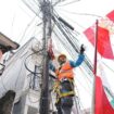 Salah seorang petugas PLN sedang merapikan bendera yang mengenai kabel listrik. (Foto : PLN Jakarta Raya)