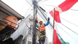 Salah seorang petugas PLN sedang merapikan bendera yang mengenai kabel listrik. (Foto : PLN Jakarta Raya)