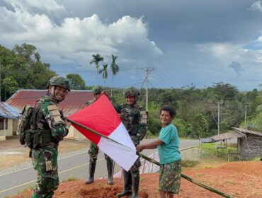 Prajurit Satgas Yonif 126/Kalacakti bersama dengan warga memasang bendera merah putih. (Foto : Puspen TNI) 