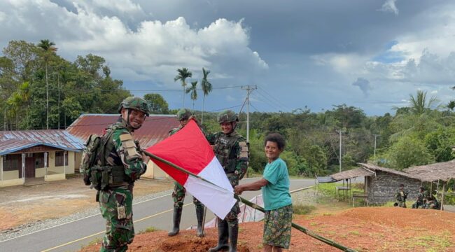 Prajurit Satgas Yonif 126/Kalacakti bersama dengan warga memasang bendera merah putih. (Foto : Puspen TNI) 