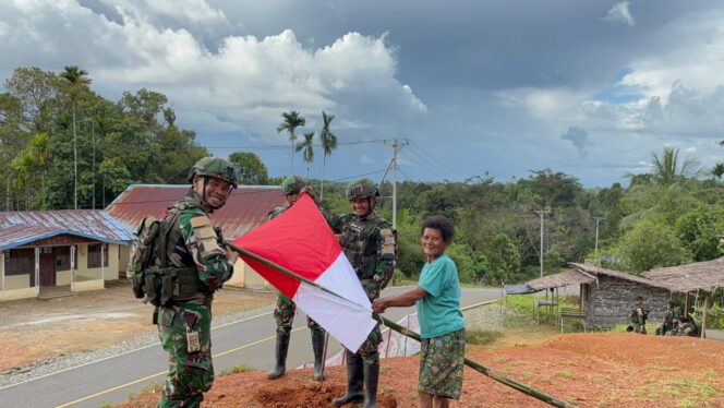 
Prajurit Satgas Yonif 126/Kalacakti bersama dengan warga memasang bendera merah putih. (Foto : Puspen TNI) 