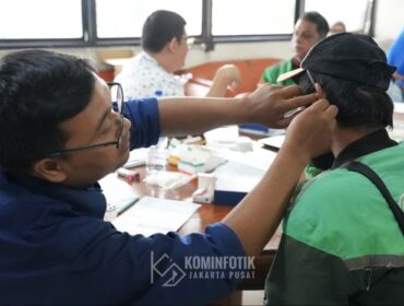 Salah saeorang staf Sudin Sosial Jakarta Pusat saat menberikan batuan alat pendengaran kepada pengemudi Ojol tuna rungu. (Foto; Kominfotik Jakpus)