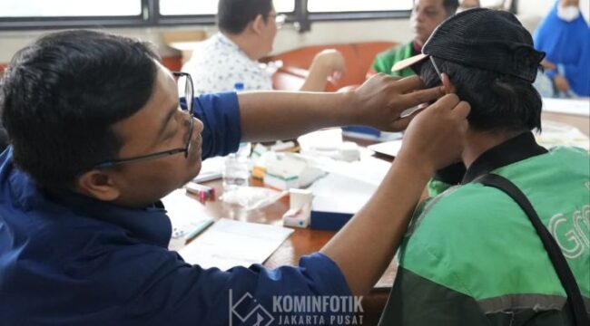 Salah saeorang staf Sudin Sosial Jakarta Pusat saat menberikan batuan alat pendengaran kepada pengemudi Ojol tuna rungu. (Foto; Kominfotik Jakpus)