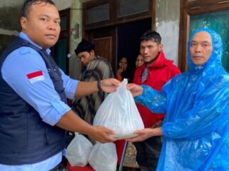 Petugas BGN saat memberikan bantuan paket MBG kepada salah seorang korban banjir di Tapanuli Selatan. (Foto : Humas BGN)