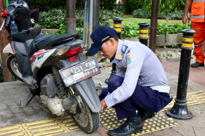 
					Salah seorang pertugas Dishub saat menindak sepeda motor yang parkir sembarangan dalam rangka Razia Rabu Tertib. (Foto : Kominfotik)