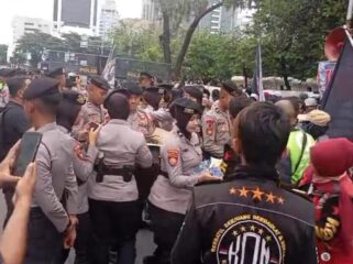 Aksi Polwan Polda Metro Jaya saat membegikan air kemasan kepada para peserta demo Ojol. (Foto : Humas Polda Metro Jaya)